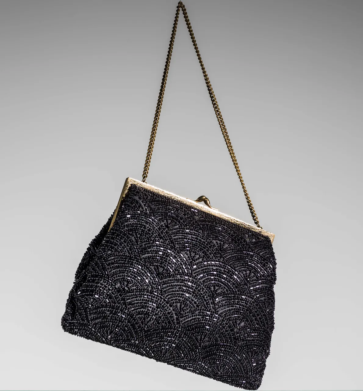 Black beaded evening bag with a gold chain, fan-scale bead pattern.