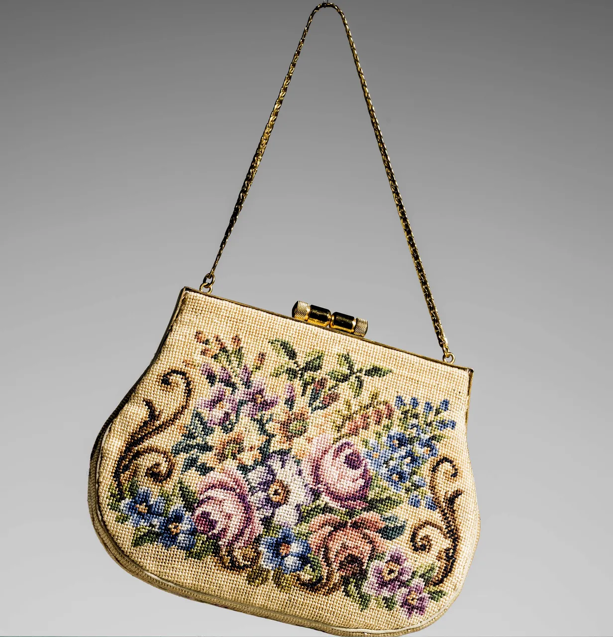 Cream petit-point evening bag with a floral bouquet and gold barrel clasp, photographed in 2014.